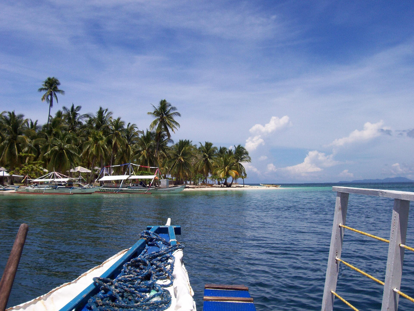 Outrigger approaching a palm island in Honda Bay